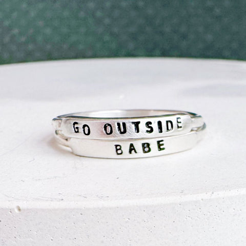 Handmade GO OUTSIDE ring by Christina Kober featuring a minimalist design and silver finish, shown on a finger.