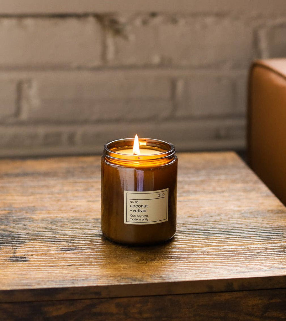 Dilo No. 05 Coconut + Vetiver candle with a white wick in a glass holder, showcasing a warm, inviting candle interior.