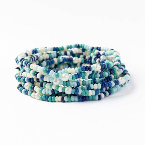 Stack of 10 blue confetti beaded bracelets by Ink + Alloy, featuring colorful beaded designs on elastic cords