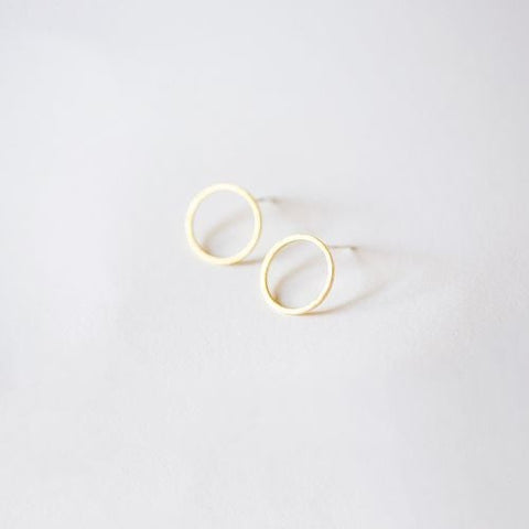 Close-up of Nude San Francisco open circle gold stud earrings on earlobes, showcasing minimalist jewelry design.