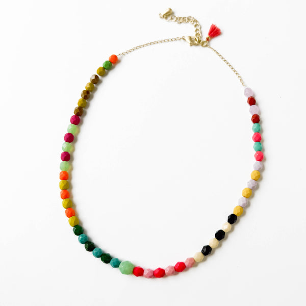 Adjustable bead necklace by Nest Pretty Things featuring a green bead and tiny tassel, styled on a neutral background.