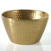 A hammered brass bowl with a textured, metallic finish, photographed on a clean white reflective surface.