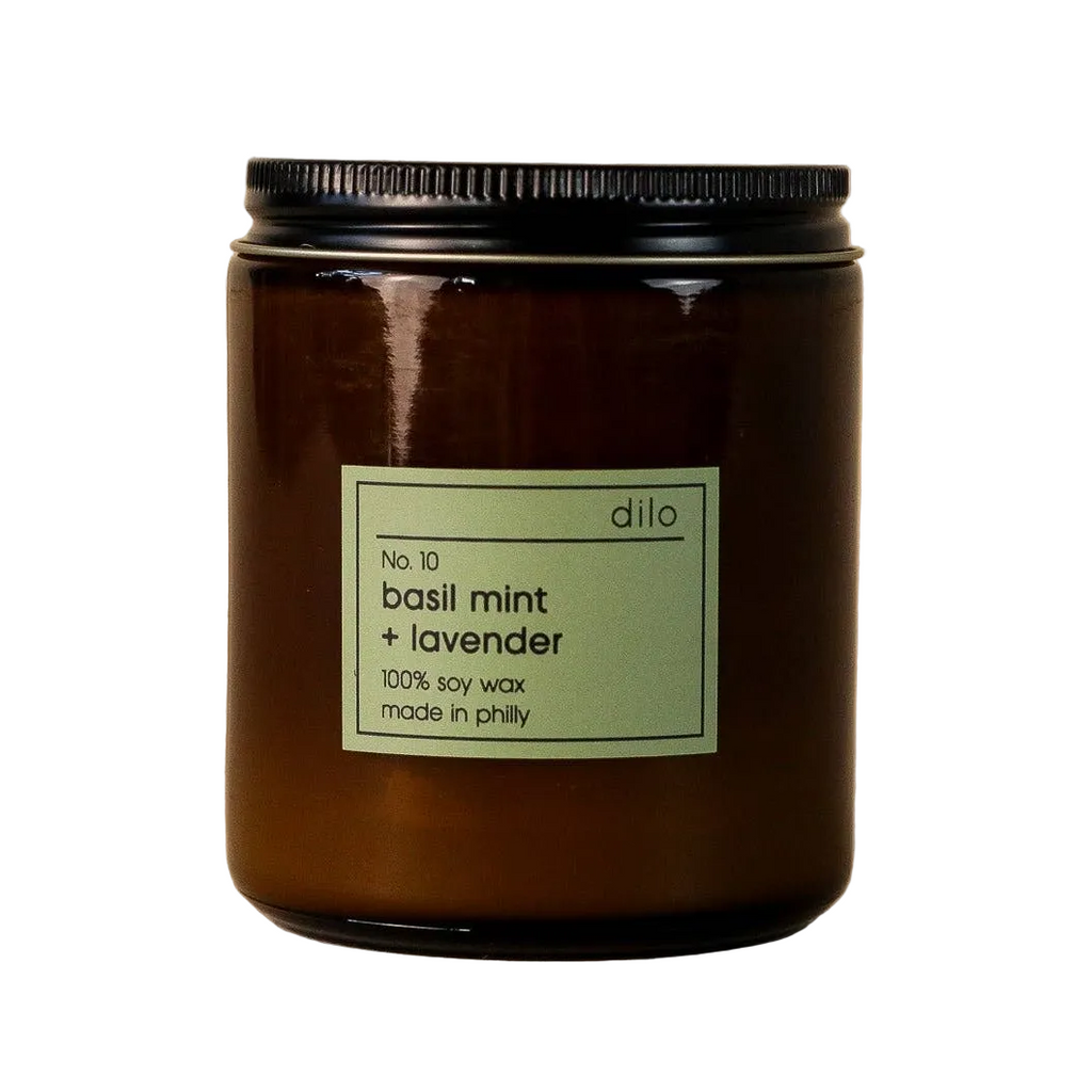 Dilo No. 10 Basil Mint and Lavender scented candle in a glass jar, with fresh herbs and lavender flowers around it.