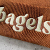 The Silver Spider Bagels embroidered beanie winter hat with colorful bagel design, knit fabric, and snug fit for cold weather.