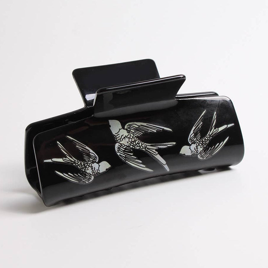 Black hair clip with bird designs on a white background