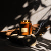 Dilo No. 03 Tobacco + Cedar candle in a glass jar, featuring a smoky tobacco and woody cedar scent, lit with a flickering flame.