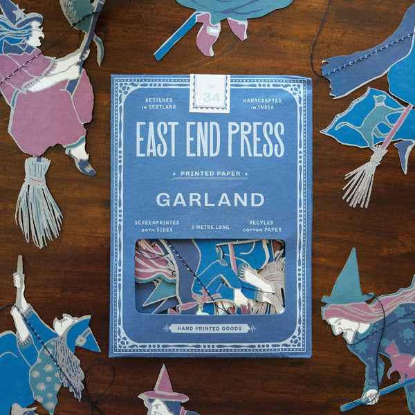East End Press Garland book surrounded by decorative cut-out figures on a wooden surface