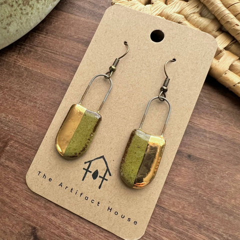 Half gold speckled olive clay earrings with a rounded, textured design from The Artifact House, shown in close-up.