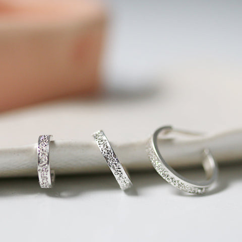 Silver Christina Kober Bold Huggie Hoop Earrings with diamond dust detail, showcasing a stylish and modern jewelry design.